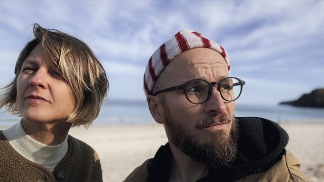 Dita Zipfel und Finn-Ole Heinrich am Strand, beide schauen zur Seite
